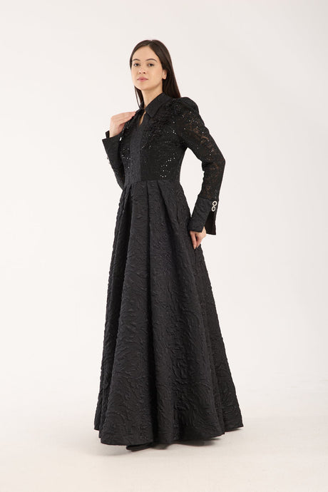 Woman wearing a long black dress with lace details on a white background